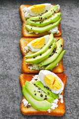 Appetizing avocado toasts with curd and egg.
