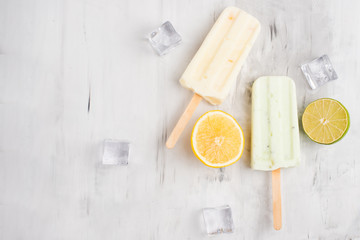 Lemon and lime popsicles on a stick. Bright color, summer mood. Eskimo with lime and lemon, refreshing and with ice on a light background. Flat-lay