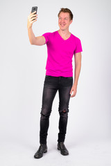 Full body shot of happy young handsome man smiling while taking selfie