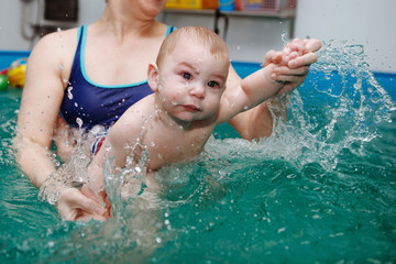 Mother with baby exercises in the pool.