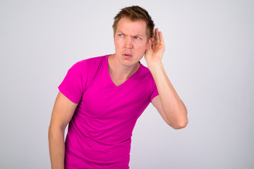 Young handsome man thinking while listening against white background