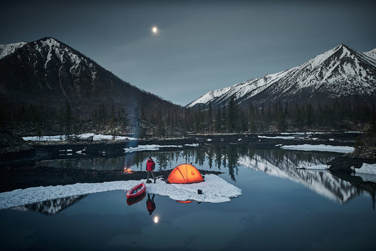 View of camp life in a mountain terrain in spring time. Lake shore with canoe
