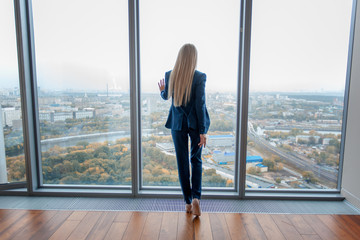 Young stylish beautiful blond business woman in a skyscraper in the office against the background...