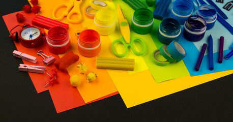 School accessories are laid out in the form of a rainbow. Black background.