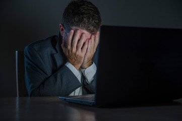 young desperate and stressed businessman working overtime at office laptop computer desk feeling anxious and overwhelmed suffering depression problem and anxiety crisis