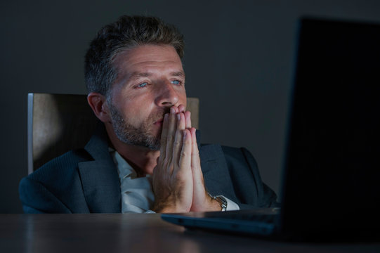 Young Excited And Attractive Businessman In Praying Hands Hoping To Win Online Bet While Working Late Night At Office Laptop Computer Desk In Internet Gambling