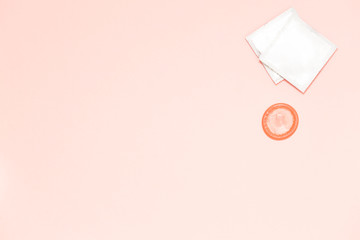 Pink opened condom and condom in pack on a pink background. A condom use to reduce the probability...