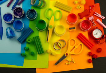School accessories are laid out in the form of a rainbow. Black background.