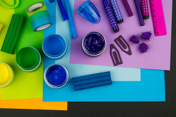 School accessories are laid out in the form of a rainbow. Black background.
