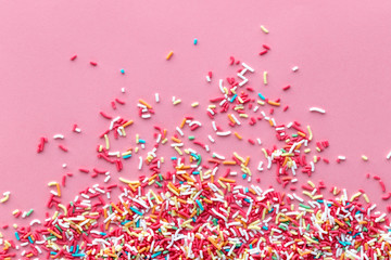Colorful sprinkles on a pink background, top view with copy space