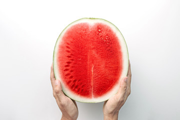 Hands holding a half of red watermelon on a white background, top view with clipping path