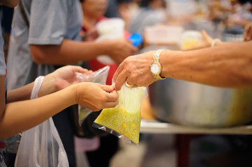 Obraz premium Hand offered to donate food from a rich man Share : Feeding Concepts
