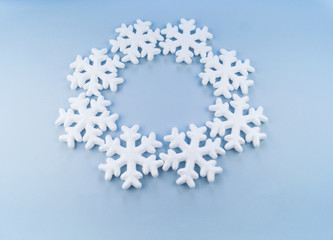 A wreath in a circle of decorative snowflakes on a blue background.