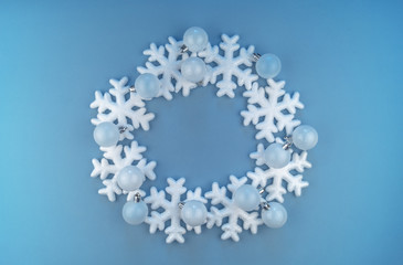 A wreath in a circle of decorative snowflakes on a blue background.