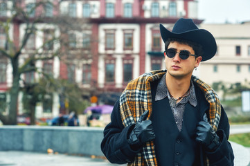 portrait of a stylish man on the street . man in black coat, plaid scarf and hat