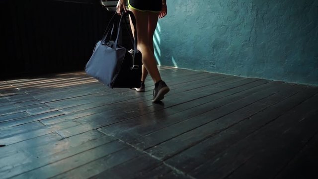 Slow motion fit young woman legs entering gym with sports bag, preparing for boxing training. Female boxer athlete on floor, taking bandage tape. wellness, fighting, motivation, self defense concept