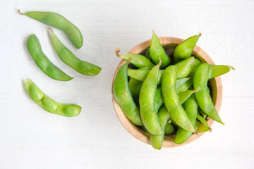 Edamame, japanese green beans in wooden bowl on white background