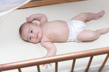 infant boy is lying in a baby crib
