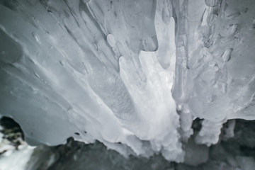Winter Baikal. Olkhon Island. Ice grotto. Thick blue ice and icicles on the coastal rocks of Olkhon...