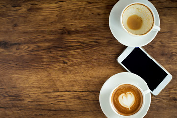 Smart phone with latte art coffee on wooden background