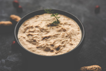 Healthy Peanut chutney made using Groundnut / Shengdana or mungfali. served in a small bowl with raw whole. Selective focus