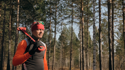 Training an athlete on the roller skaters. Biathlon ride on the roller skis with ski poles, in the helmet. Autumn workout. Roller sport. Adult man riding on skates.The athlete goes and holds sports