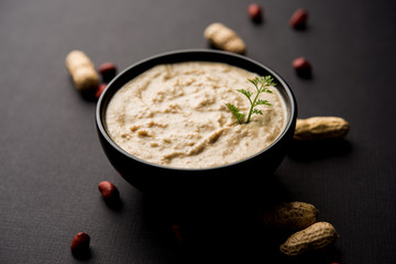 Healthy Peanut chutney made using Groundnut / Shengdana or mungfali. served in a small bowl with raw whole. Selective focus