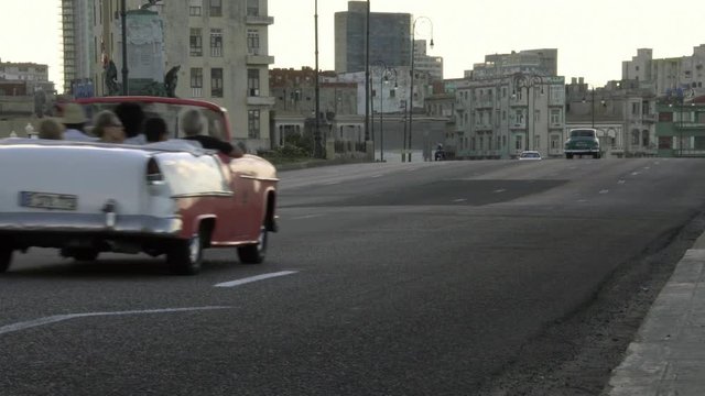 Row of iconic classic 1950's American vintage convertible car driving on waterfront malecon street in old Havana, Cuba