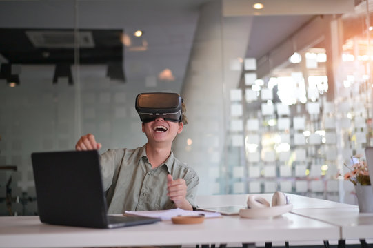 Worker Man Wearing Virtual Reality Goggles In Modern Office With Relax Time Excited Technology Concept.