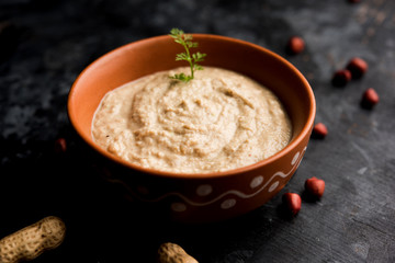Healthy Peanut chutney made using Groundnut / Shengdana or mungfali. served in a small bowl with raw whole. Selective focus