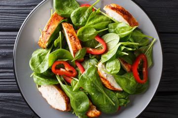Close up of a dietary salad of fresh baby spinach, chicken breast and bell pepper on a plate. horizontal top view