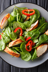 Close up of a dietary salad of fresh baby spinach, chicken breast and bell pepper on a plate. Vertical top view