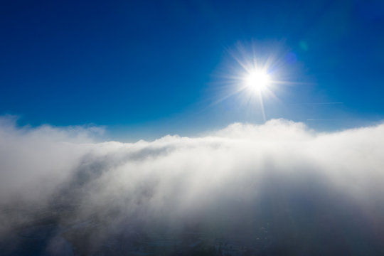 Sun rising above clouds in blue sky. Aerial cloudscape