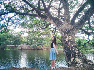 Freedom woman arms raised happy the fresh air with big tree and green nature.