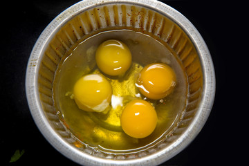 Egg yolk of four eggs in a steel bowl for beating to prepare an omlette