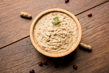 Healthy Peanut chutney made using Groundnut / Shengdana or mungfali. served in a small bowl with raw whole. Selective focus
