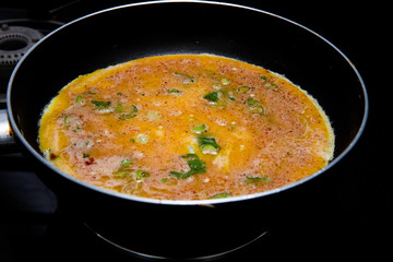 cooking omlette in Indian style with green chili , corriander leaves and lot of spices in a non stick pan