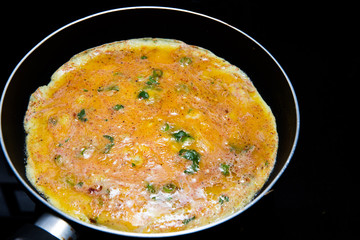 cooking omlette in Indian style with green chili , corriander leaves and lot of spices in a non stick pan