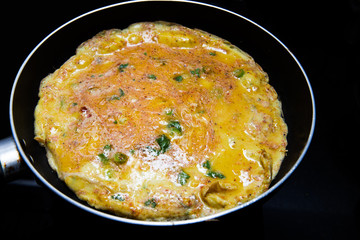 cooking omlette in Indian style with green chili , corriander leaves and lot of spices in a non stick pan