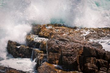 Huge wave crashing rocky coastline in Hermanus, South Africa