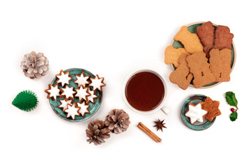 A photo of Zimtsterne and Spekulatius, traditional Christmas cookies, shot from the top on a white background with hot chocolate, spices, a toy Christmas tree, pine cones, and a place for text