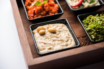 Group of Indian Chutneys includes coconut, Peanut, green and red chilly, garlic and pudina served in small square shape bowls. selective focus