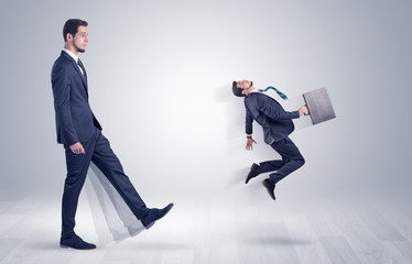 Big man in suit kicking out little himself with simple white wallpaper
