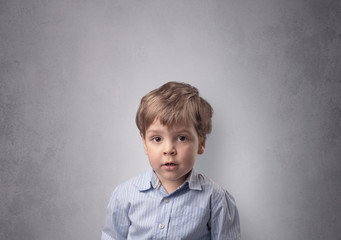 Fototapeta premium Adorable little boy portrait with empty grey wall background