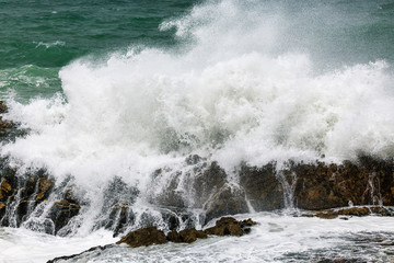 Huge wave crashing rocky coastline in Hermanus, South Africa