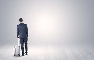 Young businessman in a white boundless space walking with back and luggage on his hand
