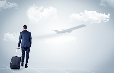 Obraz premium Young businessman with luggage walking towards an looking to a raising airplane 
