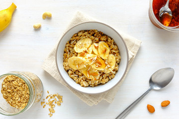 Bowl of oatmeal with banana against white table