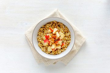 Bowl of oatmeal with apple against white table