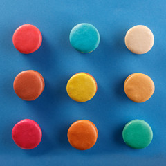 Creative layout of colorful macaroons on a blue background. Flat lay. Nutrition concept.